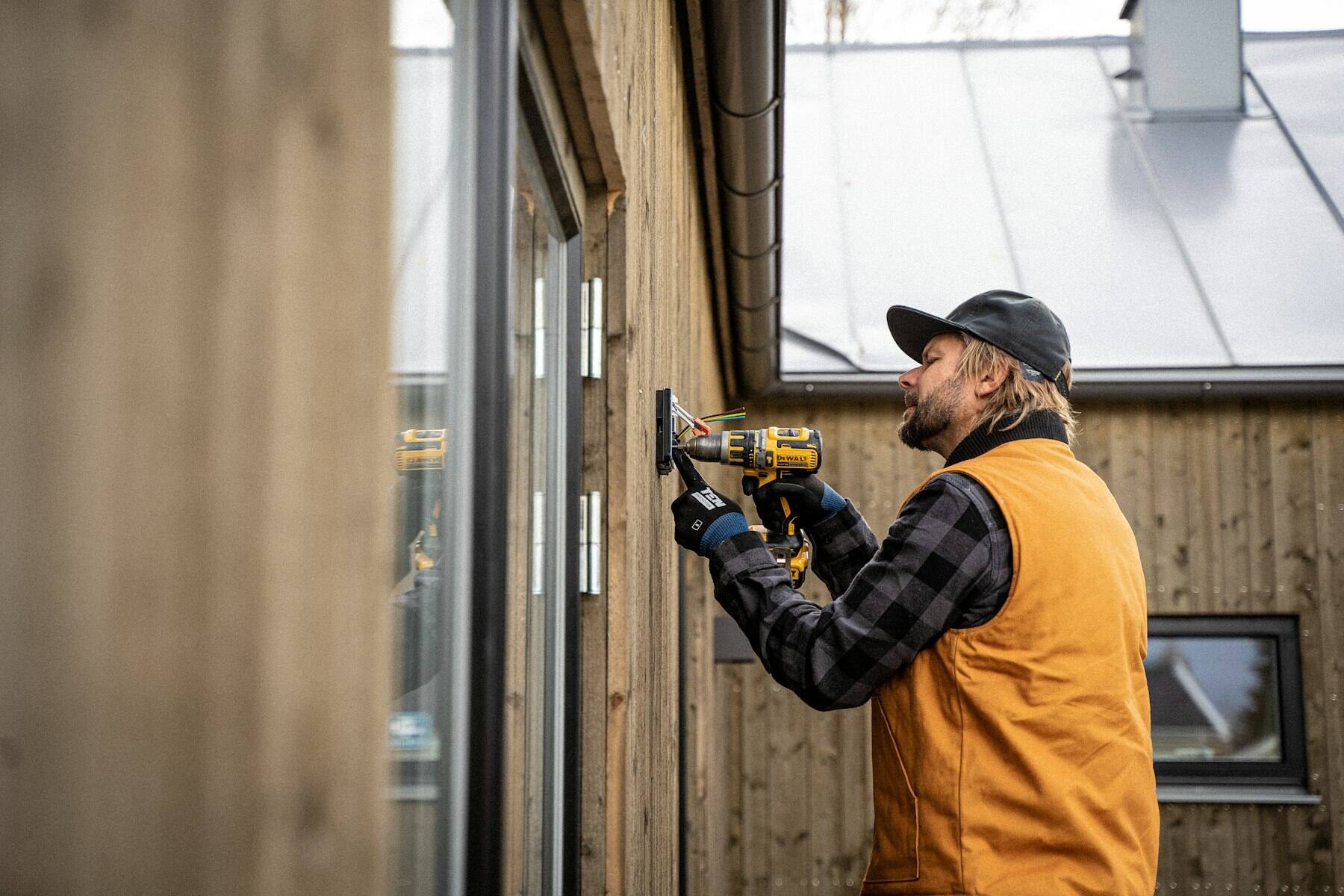 Kiwi Security technician installing a device on the outside of a timber house